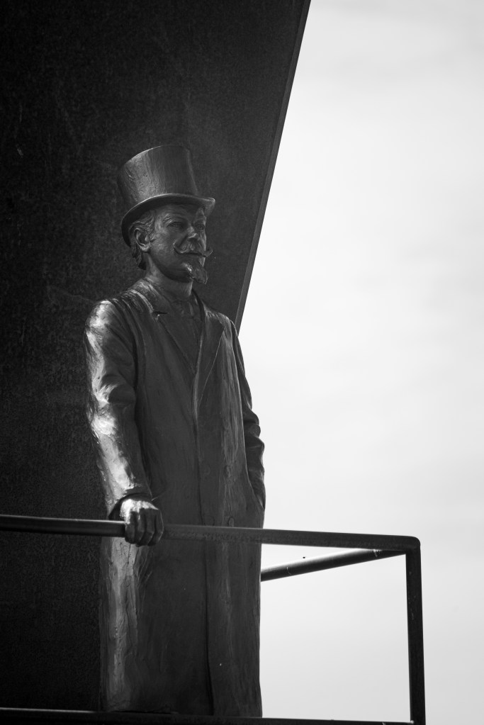 Black-and-white photo of the statue of a man wearing a top hat