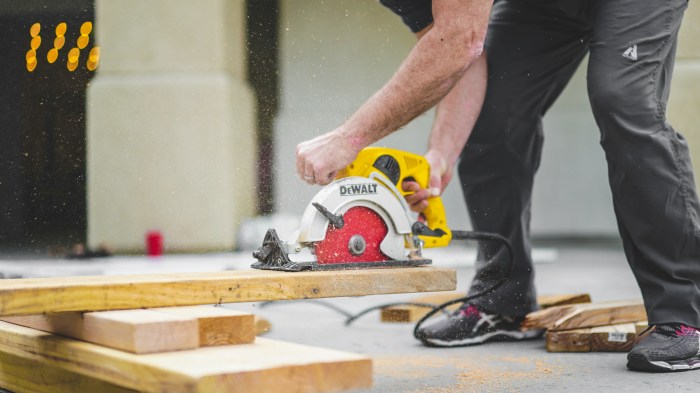 Photo of a man using a power saw to cut a piece of lumber