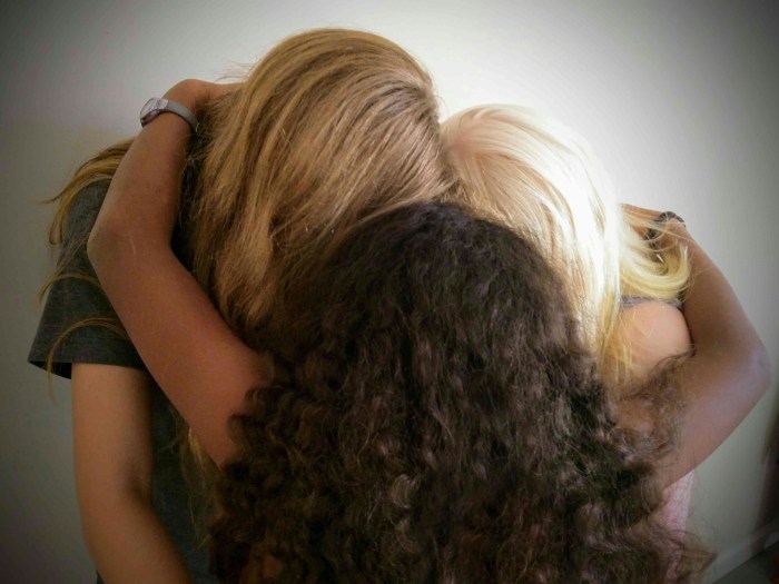 Photo of the tops of three heads: a blonde, a brown, and a black haired and skinned group of people