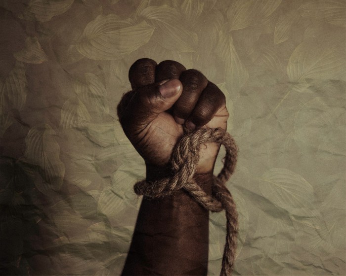 Photo of a rope around an up held wrist below a fist