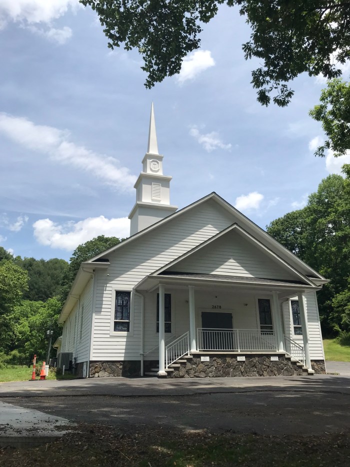 Photo of Tuckerdale Baptist Church in Ashe County, NC. A white frame church with stained glass windows and a white steeple.