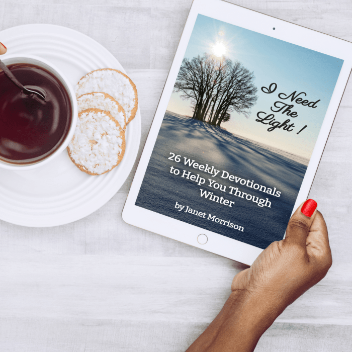 Photo of a woman's hand holding a e-book of I Need The Light! 26 Weekly Devotionals to Help You Through Winter, by Janet Morrison