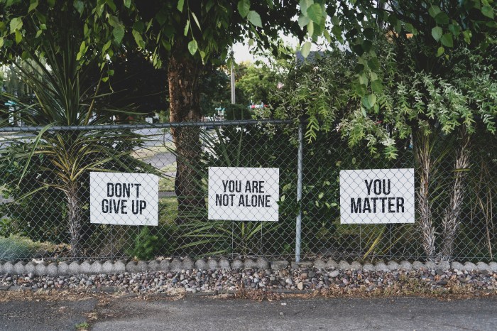 Photo of a fence on which three signs hang: Don't give up, You are not alone, and You matter.
