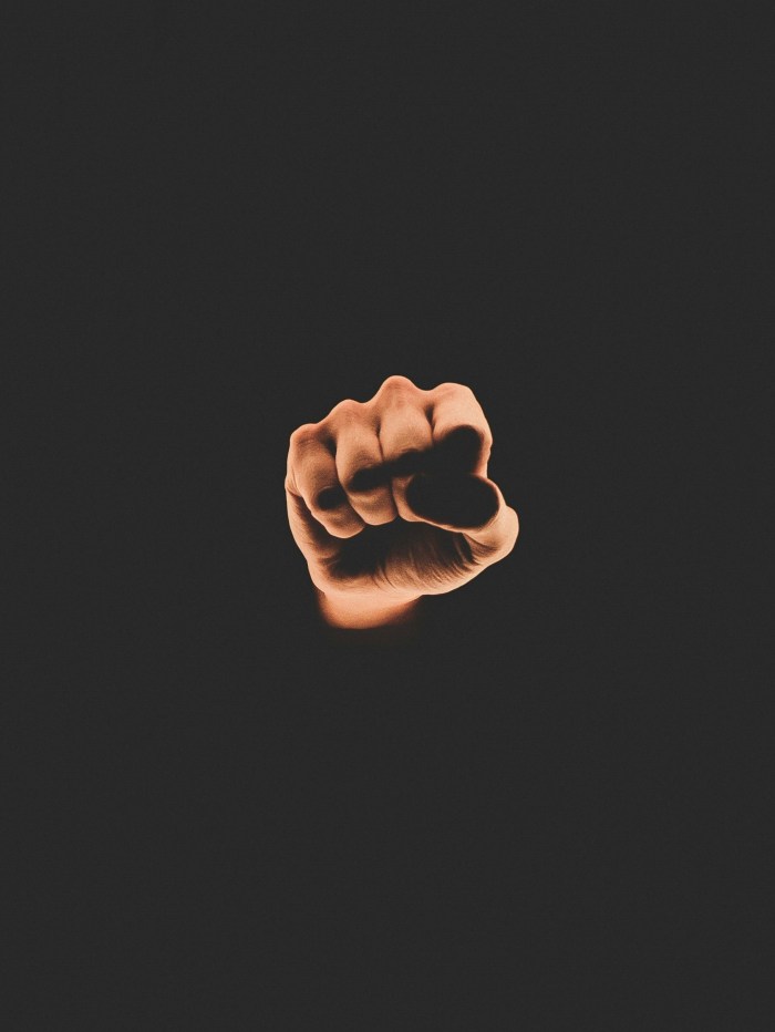 Photo of a white clinched fist coming out of a solid black background because Donald Trump often raises his fist deviantly.