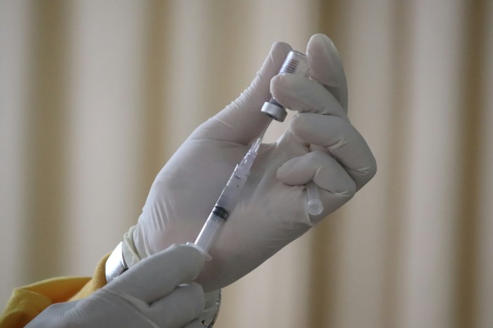 Photo of gloved hands holding a hypodermic needle